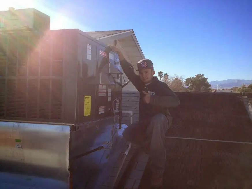 HVAC technician performing AC Tune-Up on a rooftop unit in Muskogee